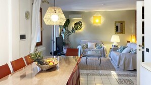 Un salon avec un canapé, une table à manger et des chaises, un téléviseur et une lampe.