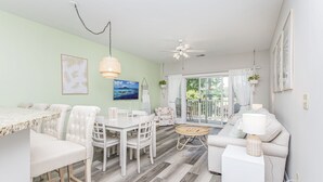 A bright living room with a dining area, white furniture, a ceiling fan, and a view through a glass door. - Golf Course Condo with Resort Style Pool, 5 Miles from Beach, Fully updated (Myrtle Beach)