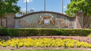 A sign for the World Tour golf links with a brick wall and a landscaped garden in front. - Golf Course Condo with Resort Style Pool, 5 Miles from Beach, Fully updated (Myrtle Beach)
