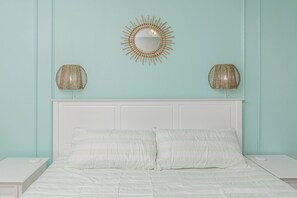 A bed with two pillows, a white headboard, and two wall-mounted lamps.
