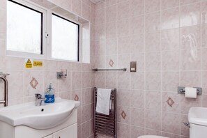 A bathroom with a white sink, a window, a towel rack, and a toilet. - Willow Chalet (Grange-over-Sands)