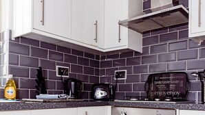 A modern kitchen with white cabinets, a black oven, and a stainless steel range hood. - Willow Chalet (Grange-over-Sands)