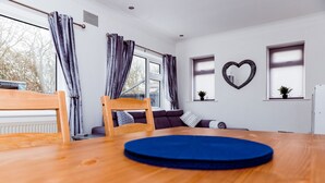 A modern living room with a wooden dining table, a sofa set, and a heart-shaped mirror on the wall. - Willow Chalet (Grange-over-Sands)