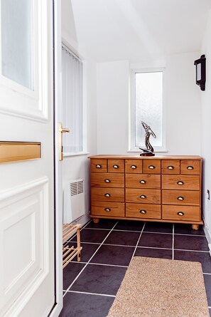 A room with a wooden dresser, a window with frosted glass, and a dark tiled floor. - Willow Chalet (Grange-over-Sands)