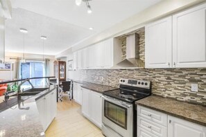 Enjoy cooking in this well-equipped kitchen with a stainless steel oven, microwave, and granite countertop.
