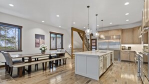 A modern kitchen with a central island, wooden flooring, and stainless steel appliances.