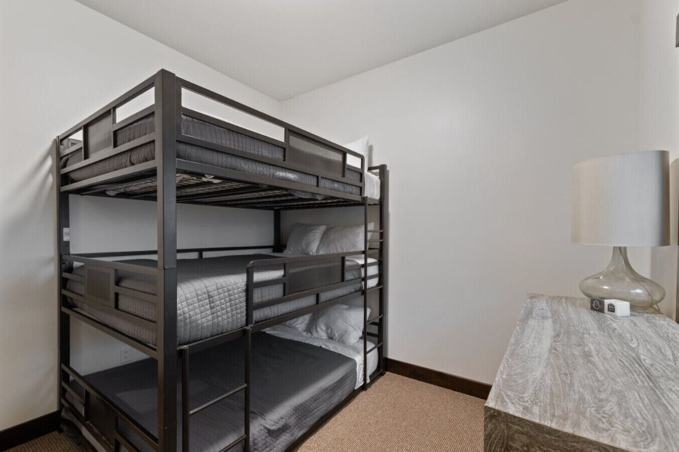 A bunk bed with a wooden frame and a bedside table with a lamp.