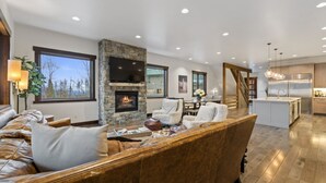 A spacious living area with a stone fireplace, leather sofas, a dining table, and a kitchen with a large island.