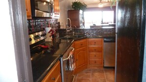 A compact kitchen with wooden cabinets, stainless steel appliances, and a tiled backsplash. - Marina Pinacate Remodeled 3 Bedroom 2 Bath Overlooking Sea of Cortez Views (Puerto Penasco)
