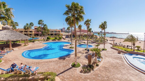 A resort with a large central pool, palm trees, and a view of the sea. - Marina Pinacate Remodeled 3 Bedroom 2 Bath Overlooking Sea of Cortez Views (Puerto Penasco)