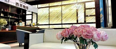 A modern interior with a reception desk, a white sofa, and a vase of pink flowers.