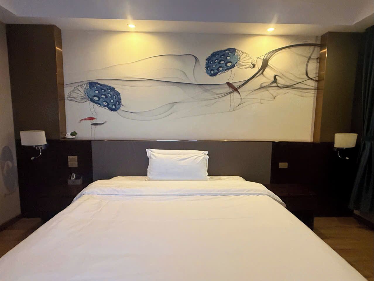 Ein Hotelzimmer mit einem großen Bett, zwei Nachttischen mit Lampen und einem Kunstwerk über dem Bett.