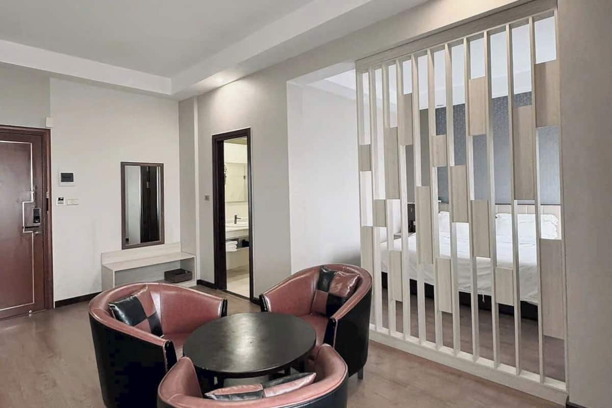 Ein modernes Hotelzimmer mit einem runden Tisch, zwei Stühlen, einem Bett und einer Schiebetür mit Blick.
