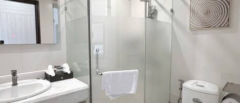 A modern bathroom with a glass-enclosed shower, a toilet, and a sink with a mirror above it.