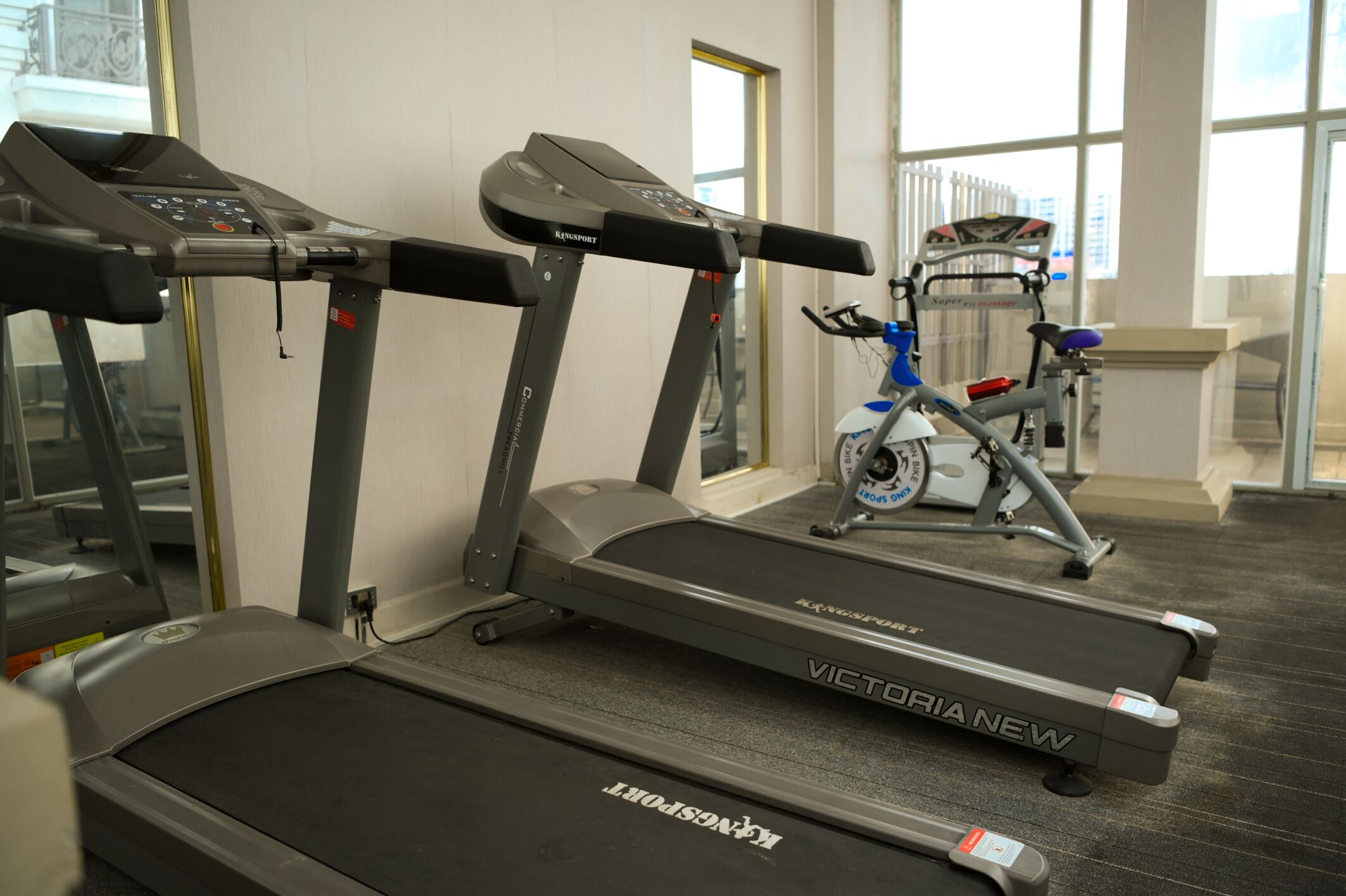 A gym with treadmills, a stationary bike, and a window providing natural light.
