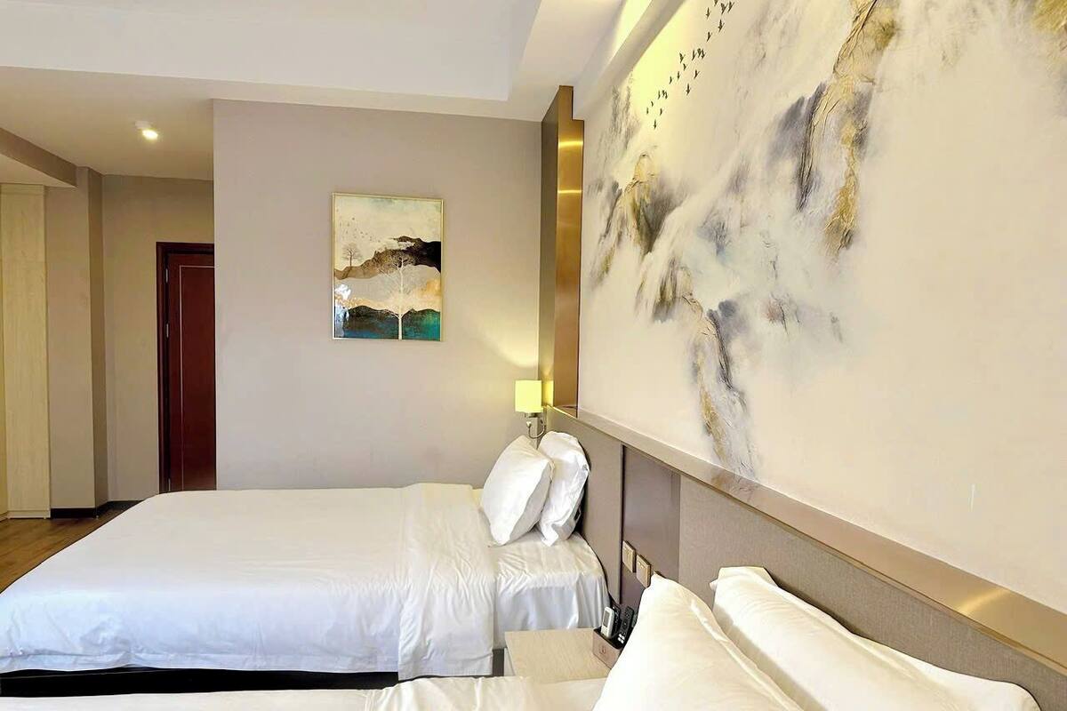 Ein Hotelzimmer mit zwei Betten, einem Bild an der Wand und einem großen, abstrakten Kunstwerk.