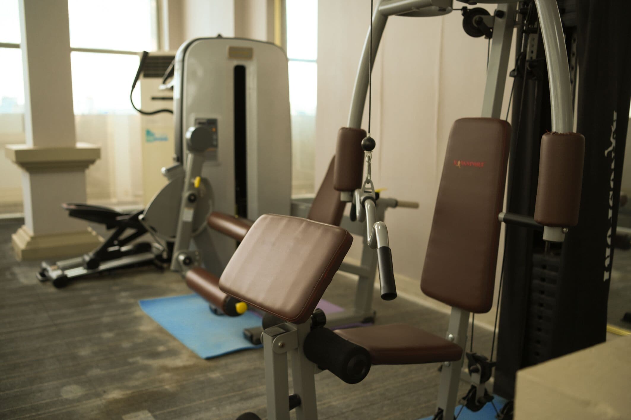 A gym with exercise equipment including a leg press machine, a chest press machine, and a bench.