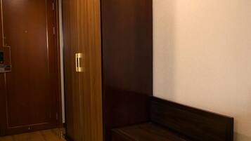 Un dormitorio con un armario de madera, un banco con zapatero y una puerta.