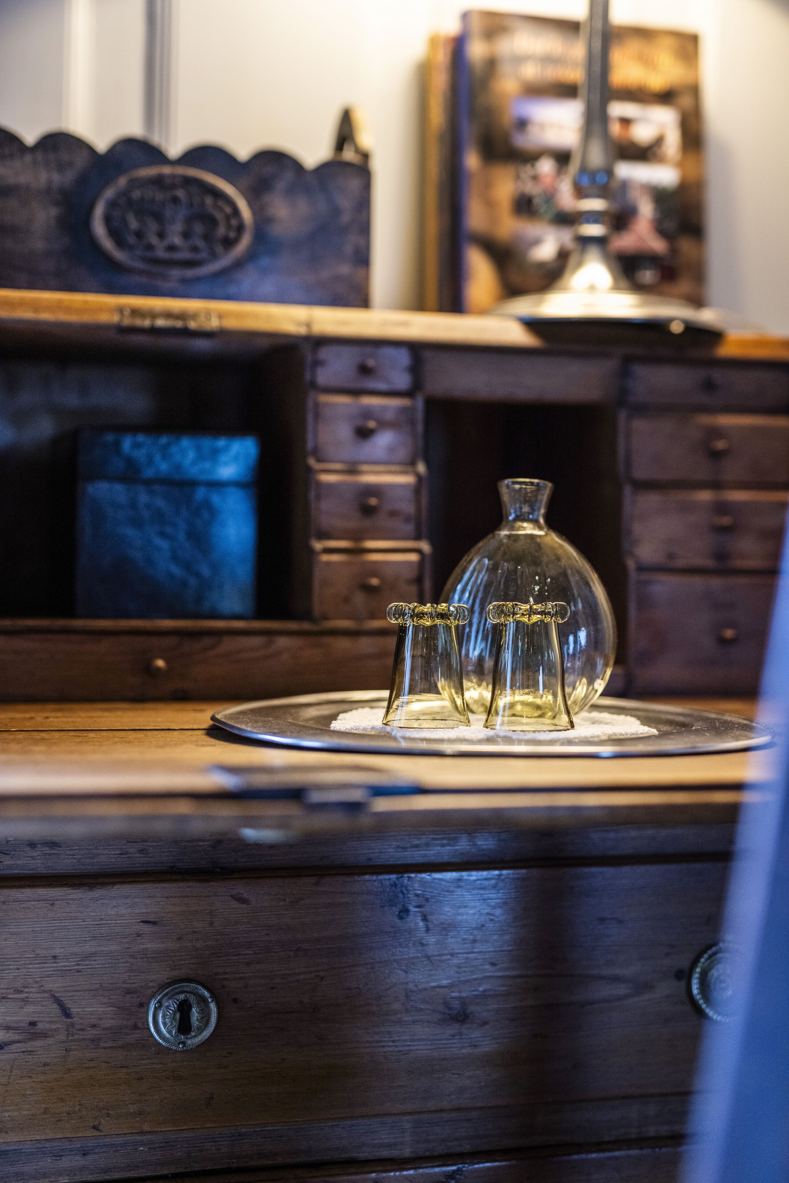 A wooden dresser with a glass bottle and three small glass vases on top.