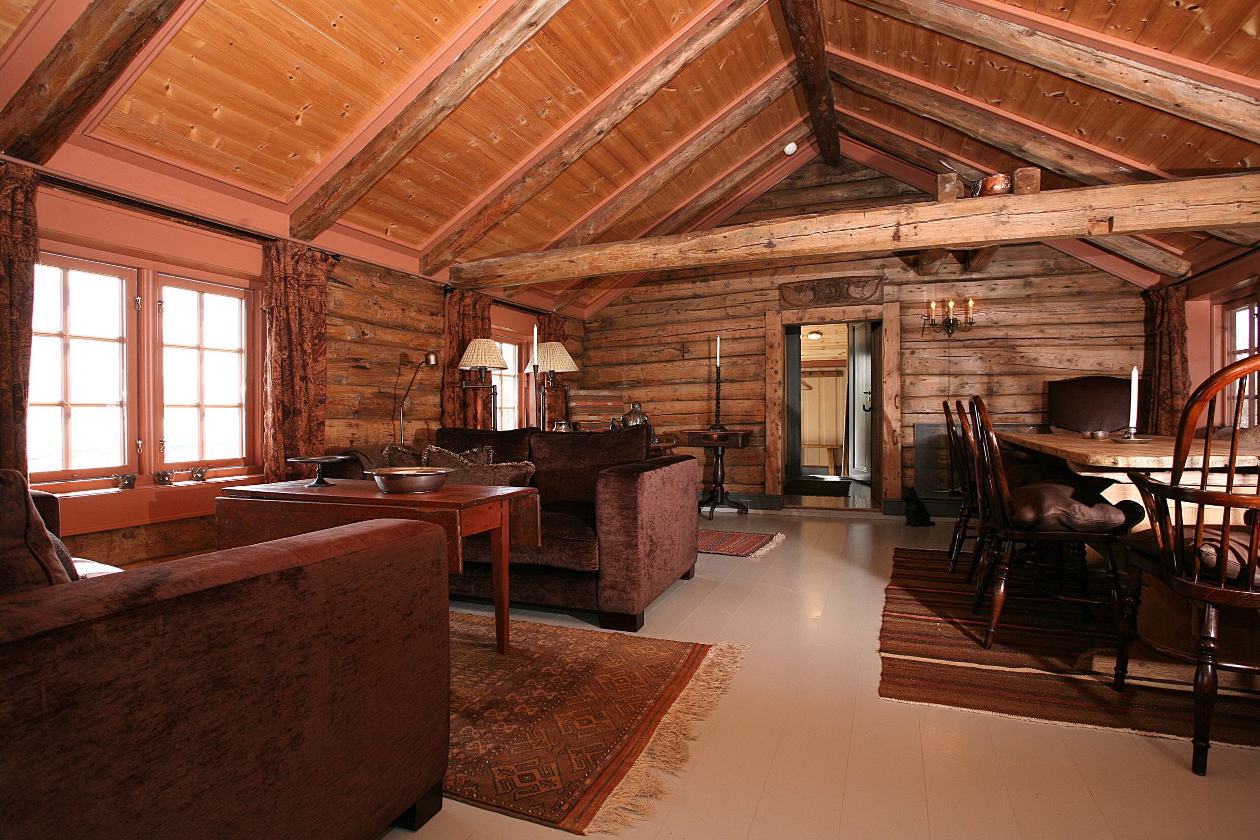 A log cabin interior with a dining area, a sofa, and a fireplace.