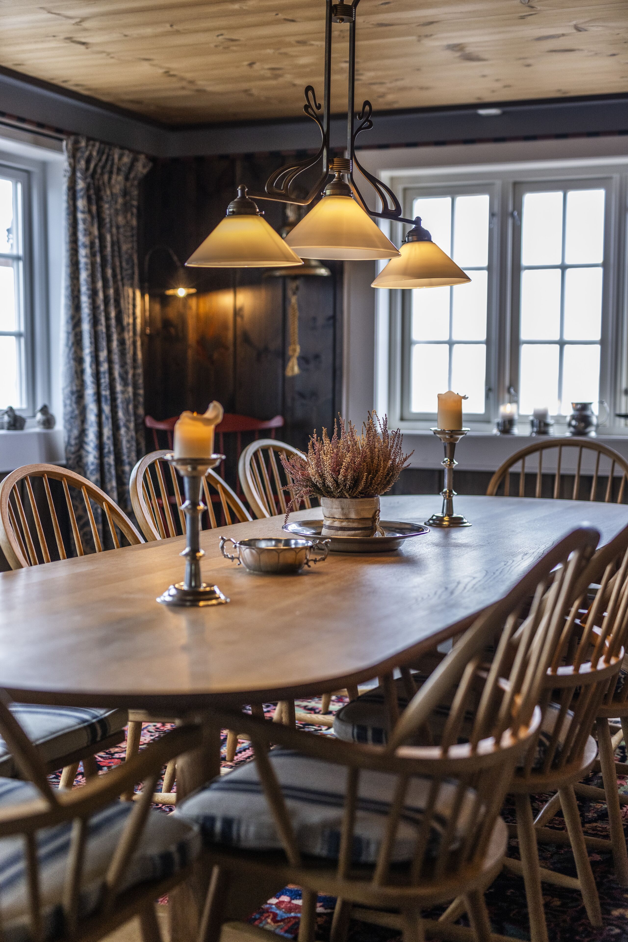 A dining area with a wooden table, chairs, and hanging lamps.