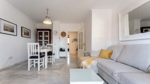 A living room with a sofa, a coffee table, a dining table with chairs, and a kitchen in the background. - "El Toro" Apartment with Ocean View, Shared Pool, and Wi-Fi (Fuengirola)