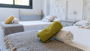 A hotel room with two beds, each with a rolled towel and a patterned bedspread. - "El Toro" Apartment with Ocean View, Shared Pool, and Wi-Fi (Fuengirola)