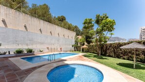 A swimming pool with a hot tub, surrounded by a patio area with a concrete wall and greenery. - "El Toro" Apartment with Ocean View, Shared Pool, and Wi-Fi (Fuengirola)