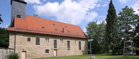 A stone building with a red-tiled roof and a bell tower.