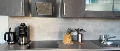 Une cuisine moderne équipée d’un four encastré, d’une machine à café et d’une hotte aspirante.