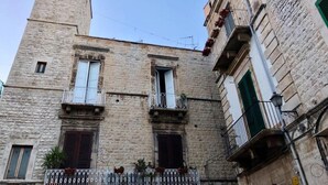 Un edificio histórico de piedra con una torre de reloj, múltiples ventanas y balcones.