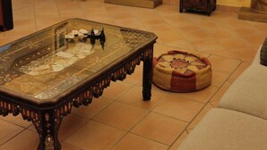 Una habitación con una mesa de vidrio, un otomán tejido y dos grandes estatuas de Buda en la pared.
