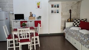 Een knus verblijf met een zithoek, kitchenette en een bed met beddengoed met een patroon.