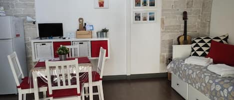 Une pièce compacte comprenant un coin repas, une kitchenette et un lit avec une literie à motifs.
