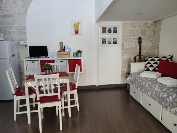 A compact room with a dining area, kitchenette, and a bed with patterned bedding.