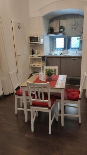 A dining area with a table and chairs, a kitchen with a microwave and sink, and a window.