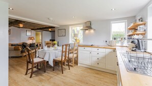 A modern kitchen with wooden cabinets, a dining area with a table and chairs, and a window providing natural light. - Bar Lane Cottage - sleeps 5 in Reepham (Reepham)