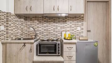 Een koelkast, een kookplaat, een waterkoker, kookgerei, borden en bestek