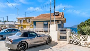 A convertible car parked in a driveway with a house in the background. - Apartment 'Oceanida Aelia Room 2' with Shared Pool and Wi-Fi (Nikiana)