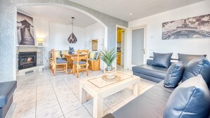 Ein Wohnzimmer mit einer Couch, einem Essbereich mit Stühlen und einem Tisch, einem Kamin und einer Wand mit einem Bild vom Eiffelturm.