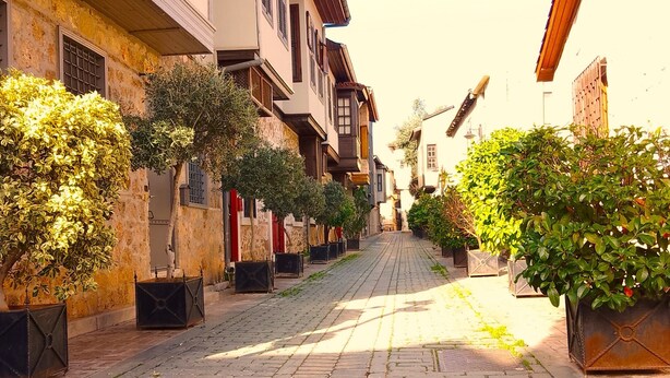 A cobblestone street lined with traditional buildings, some with balconies and potted plants. - Warm Studio Flat with Patio LOTUS (Antalya)