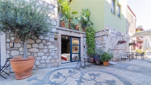 A courtyard with a stone wall, potted plants, and outdoor seating. - Warm Studio Flat with Patio LOTUS (Antalya)