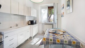 A kitchen with white cabinets, a coffee maker, and a table with a floral tablecloth.