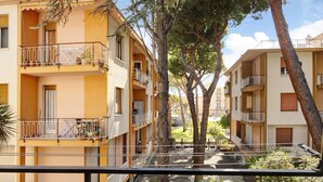 A multi-story residential building with balconies, a courtyard, and trees.