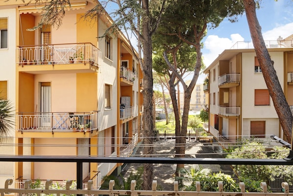 A multi-story residential building with balconies, a courtyard, and trees.