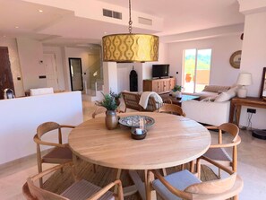 Un espace repas moderne avec une table ronde en bois, des chaises en osier et une lampe suspendue.