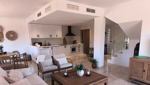 A spacious living area with a sofa set, a wooden coffee table, and a kitchen in the background. - Apartment 'Casa Sunchill' with Shared Pool, Wi-Fi and Air Conditioning (Marbella)