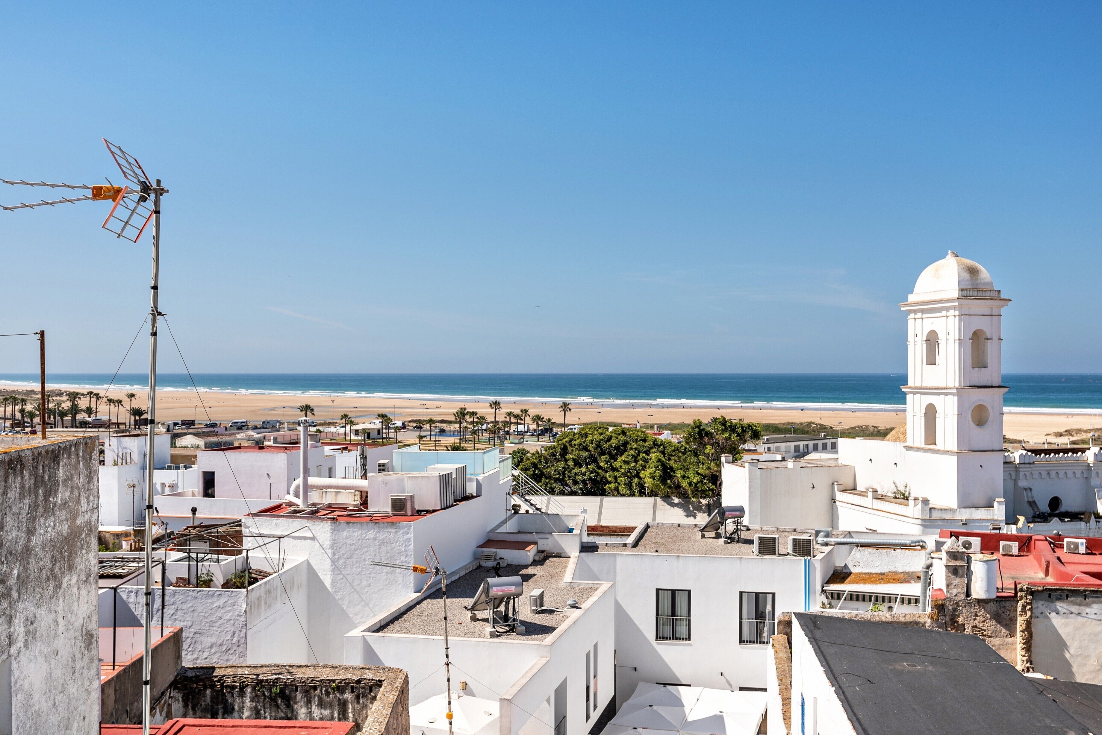 A coastal town with white buildings, a beach, and a white tower.