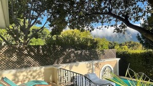 Un área junto a la piscina con sillones reclinables, una escalera y vistas a las montañas.