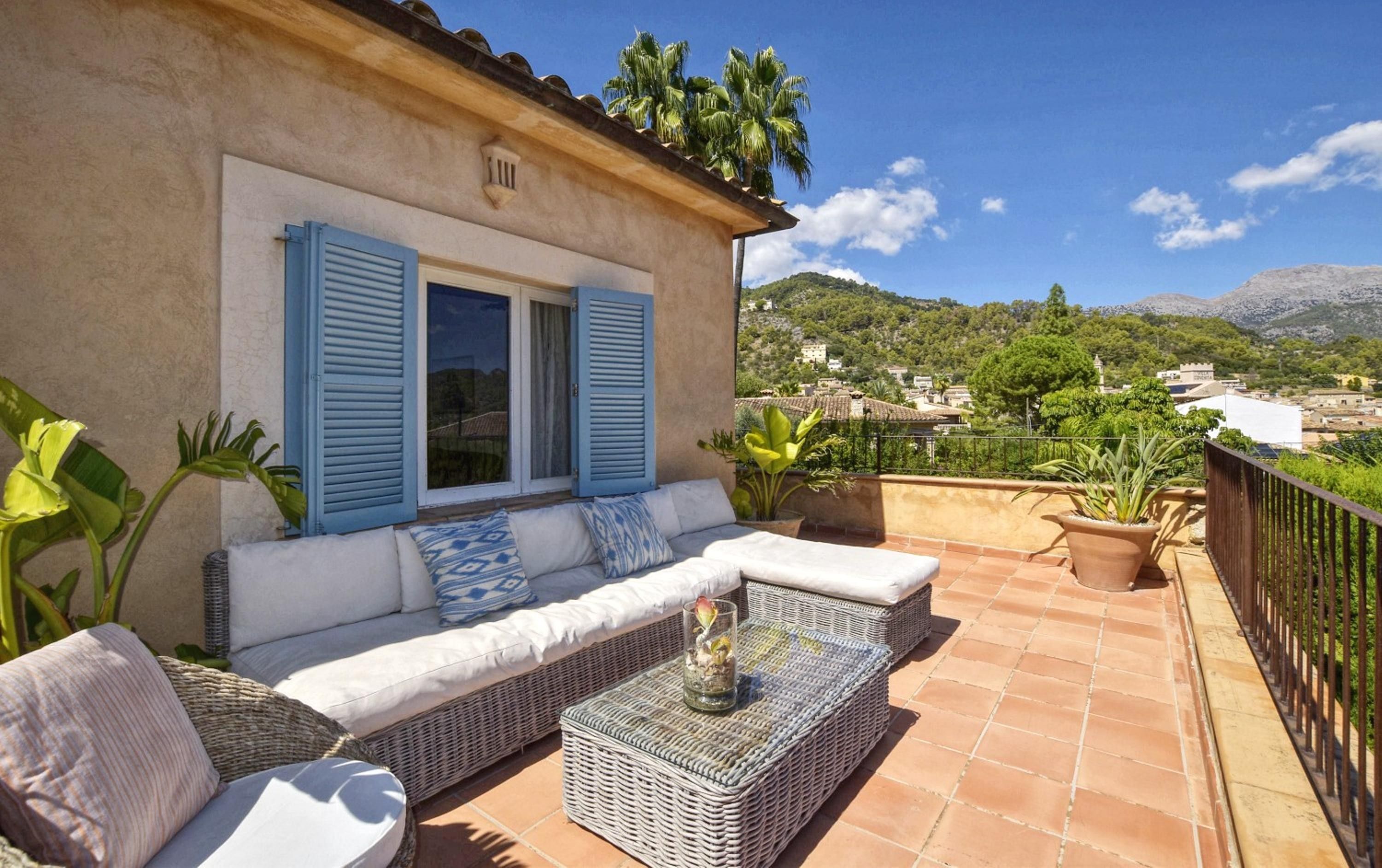 Une terrasse avec un canapé, des meubles en osier et des plantes en pot.